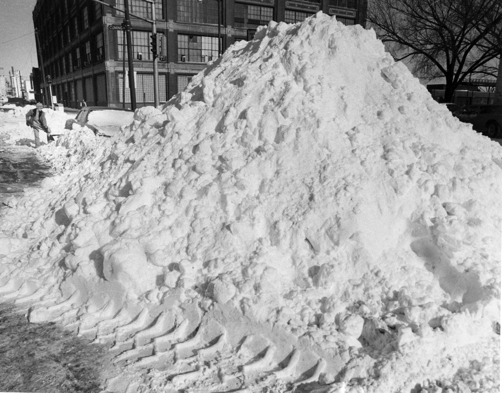 Jerry Bowen, 13, digs his parent's car out of the snow next to a 10 foot pile deposited in from parking lot at 16th and Cuming Streets on Jan. 13, 1975.